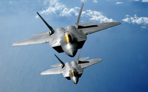 Two F-22 Raptors fly over the Pacific Ocean during a theater security mission March 9 as part of a d