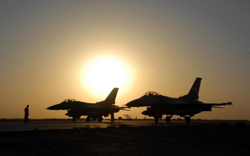 A pair of F-16 Fighting Falcons sit on the flightline as the sun sets at Balad Air Base Iraq.  F-16s