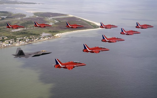 An F-22 Raptor flies with British Royal Air Force aerobatic team, The Red Arrows, during a practice 
